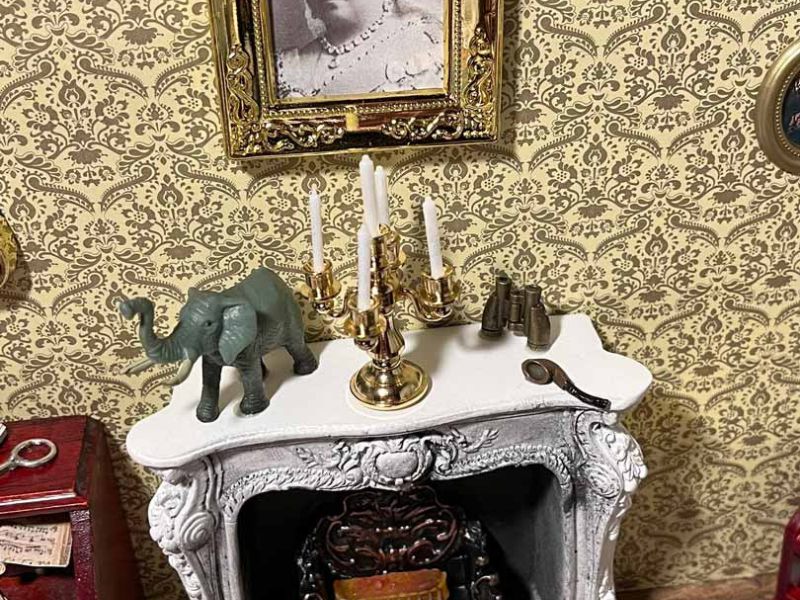 Der Kamin im Diorama von Sherlock Holmes Wohnzimmer mit kleinen Details und Wandbild.